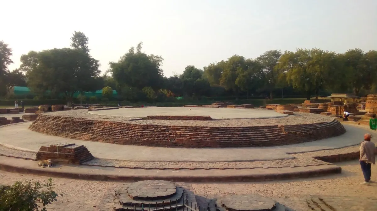 Massive cylindrical brick and stone Dhamek Stupa standing on green lawns at Sarnath, Varanasi, India