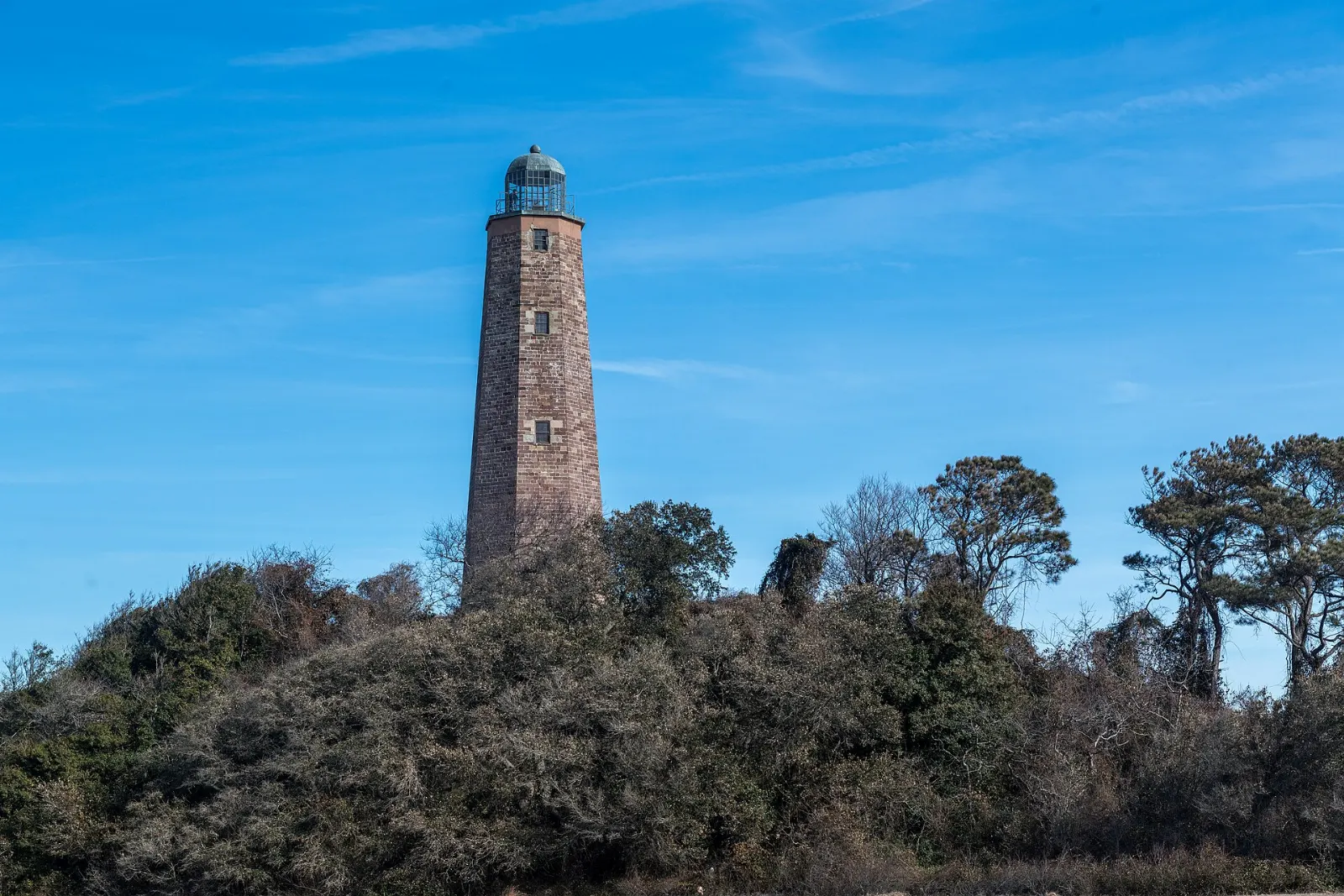 Octagonal sandstone Old Cape Henry Lighthouse on a grassy dune at the mouth of the Chesapeake Bay, Virginia Beach, Virginia