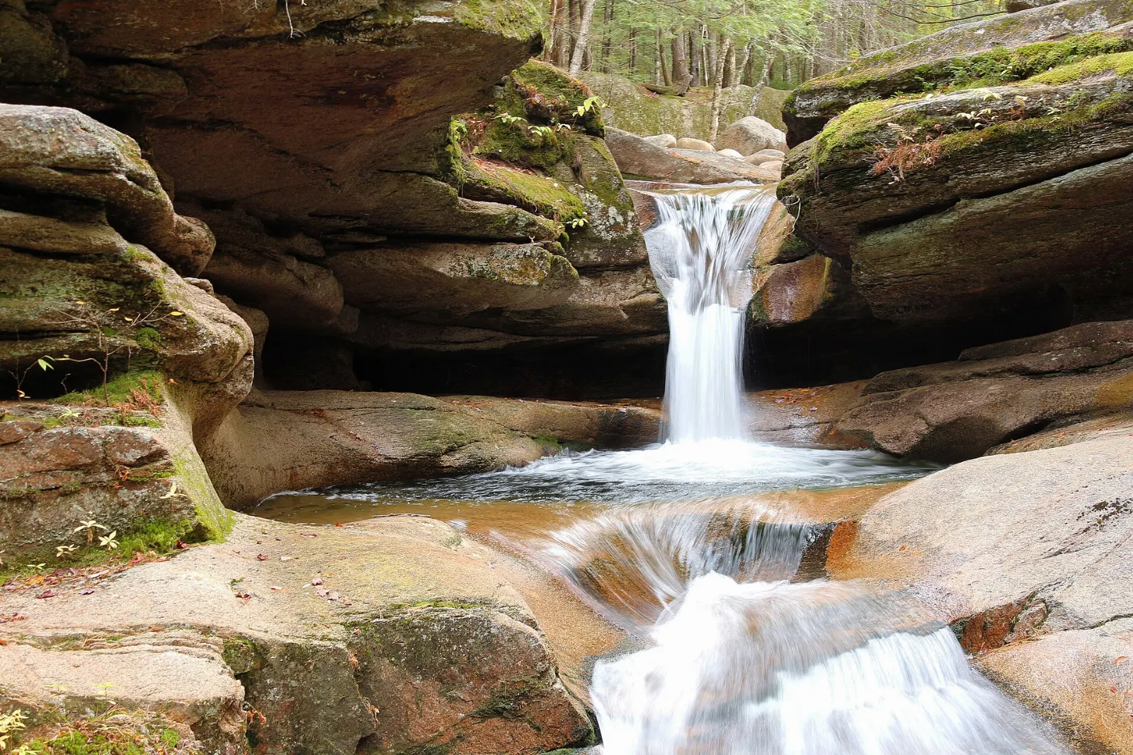 A narrow waterfall twisting through a carved rock flume in the forest, White Mountains, New Hampshire