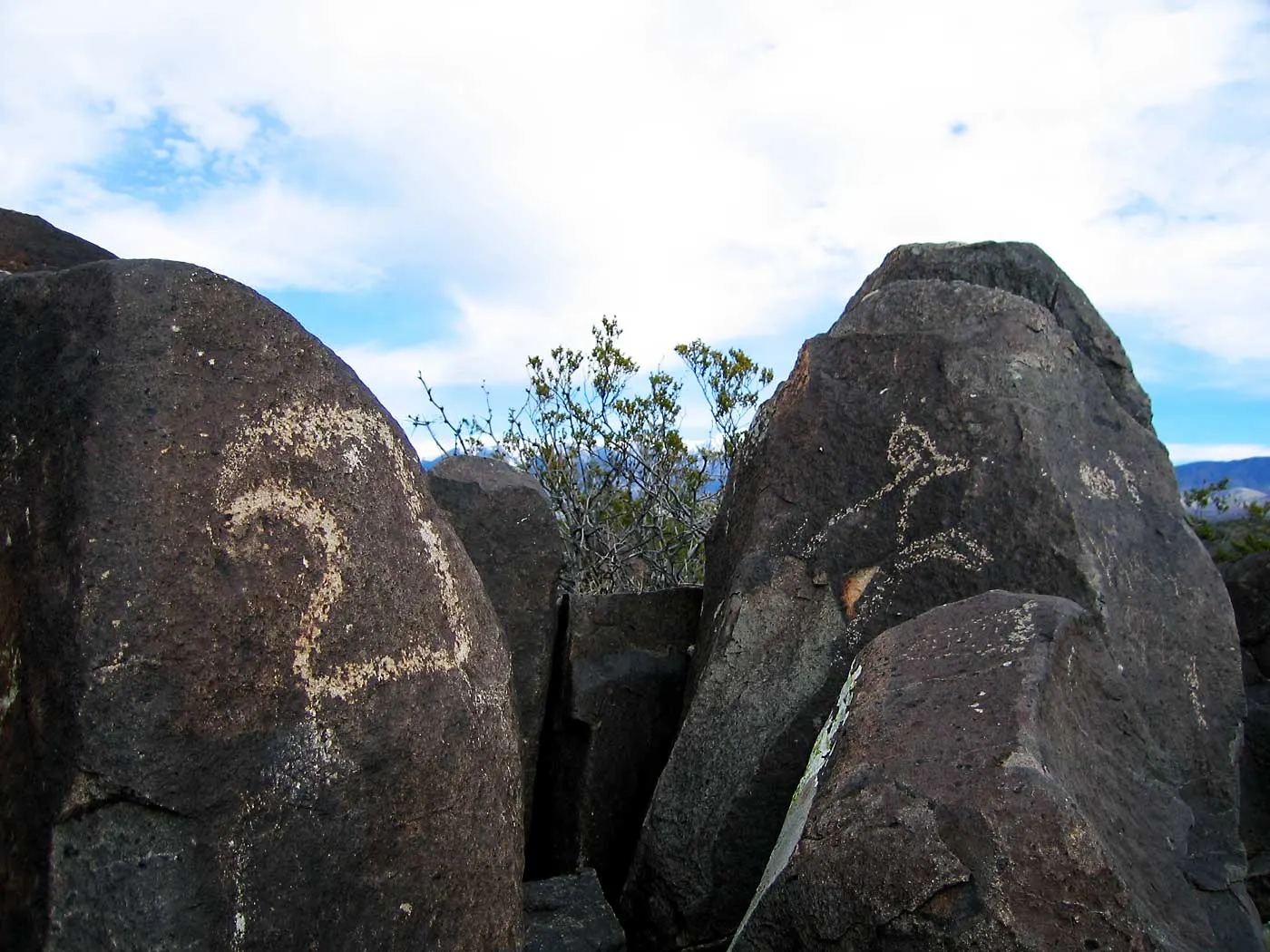 Ancient rock carvings on dark basalt boulders at Three Rivers Petroglyph Site, White Sands National Park, New Mexico