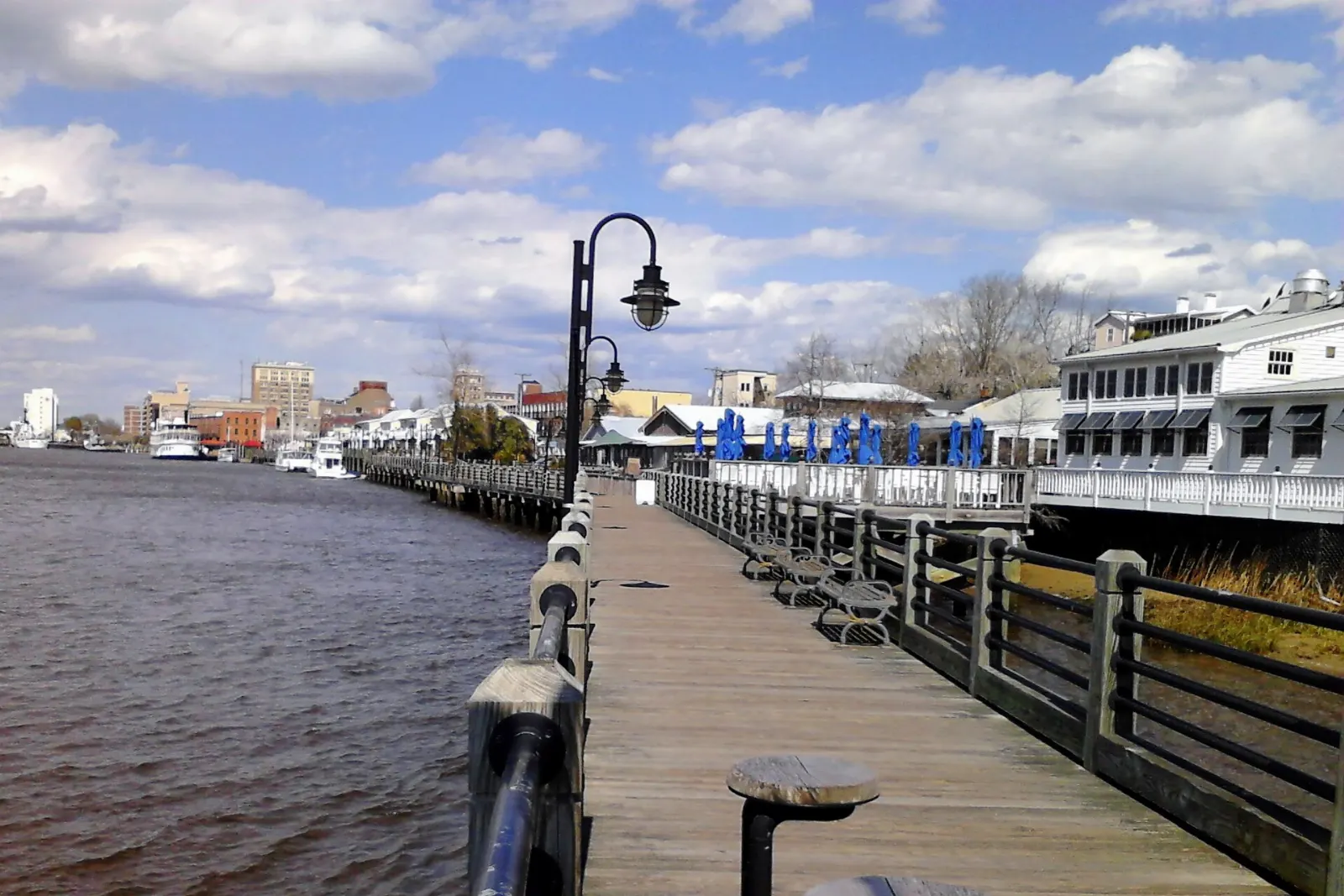 Wooden boardwalk along the Cape Fear River lined with benches and lamps, Wilmington, North Carolina