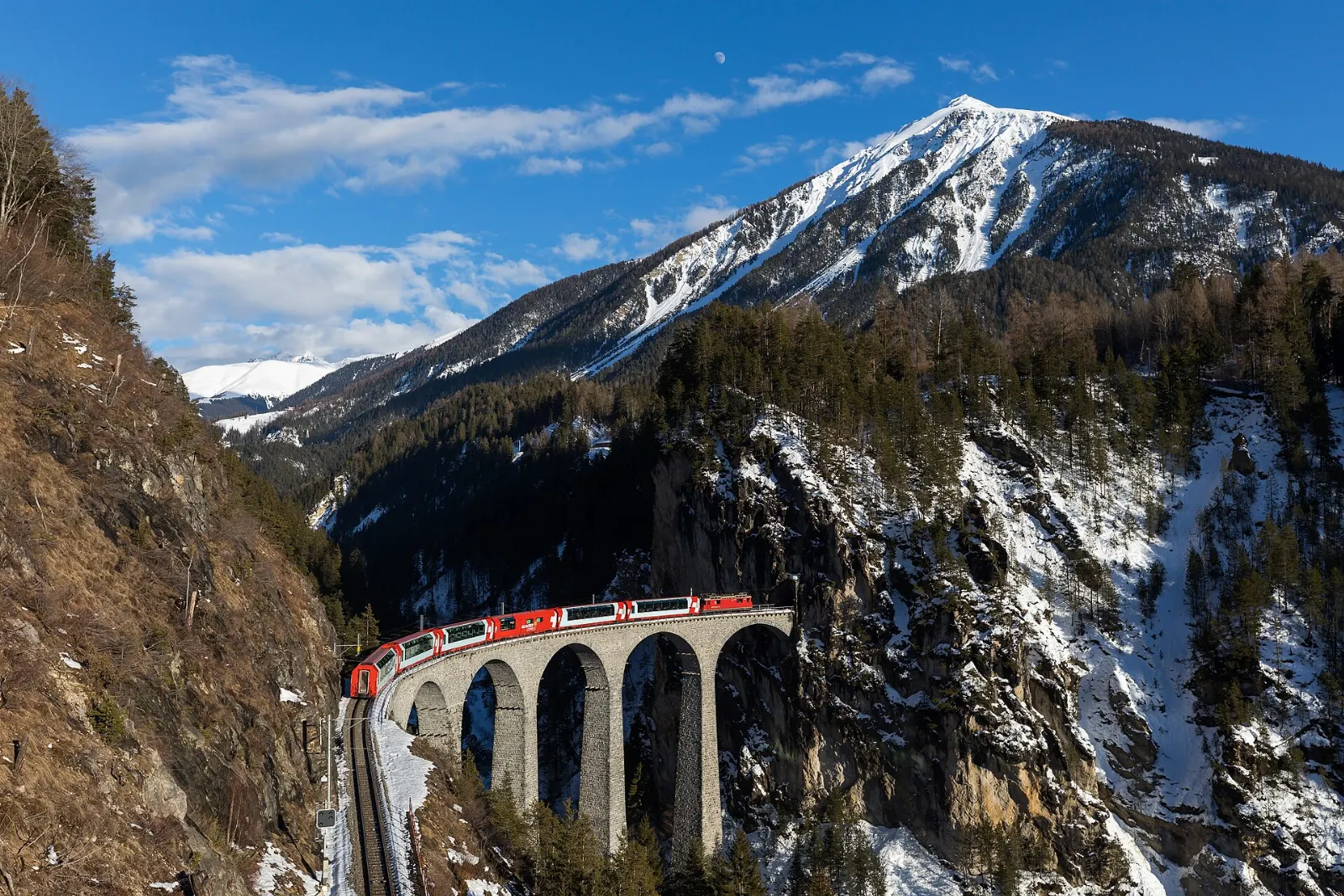 Red panoramic carriages of the Glacier Express crossing an alpine landscape, Zermatt, Switzerland